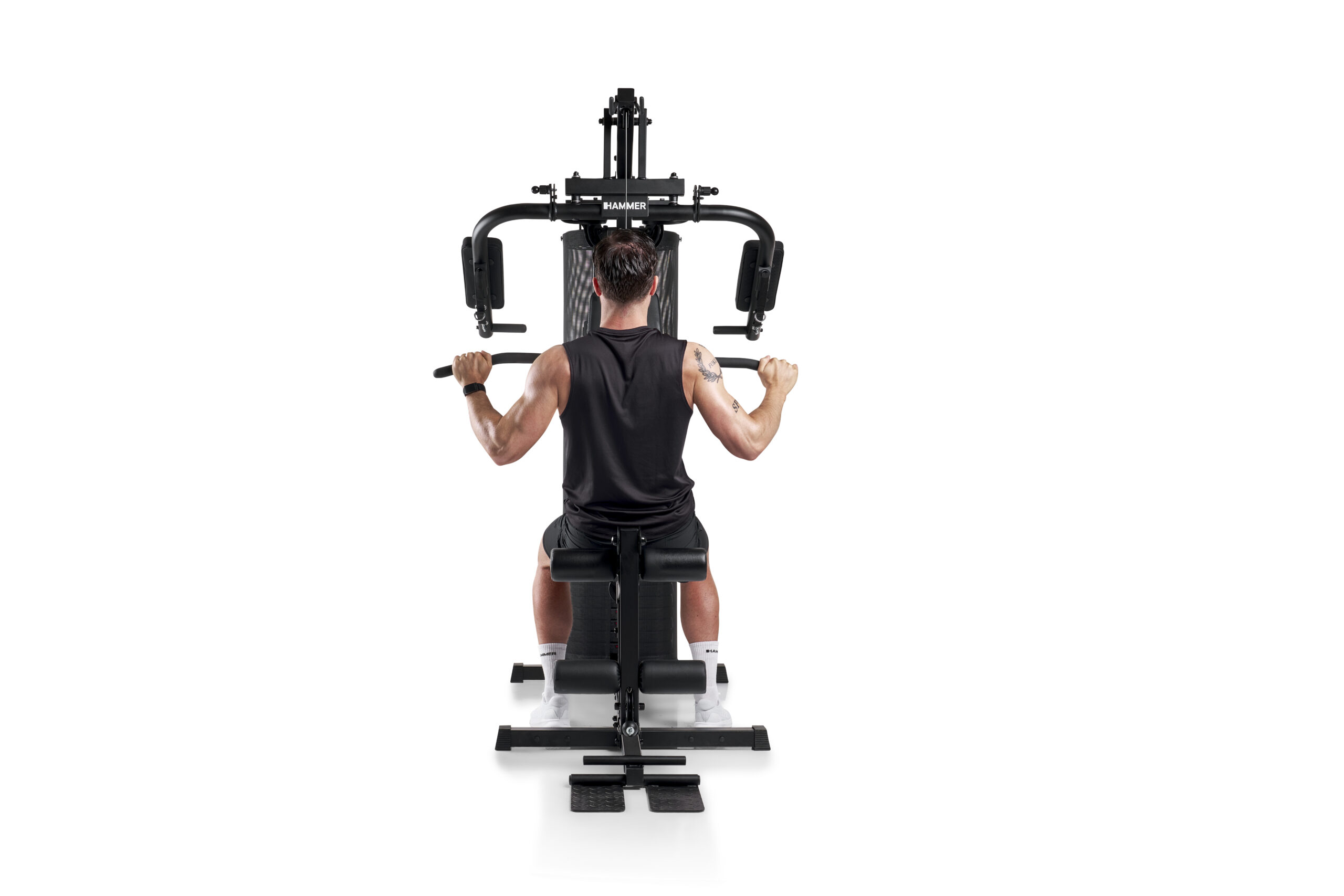 Rear view of a man in a black sleeveless shirt using a Hammer Strength weight machine, gripping handles during a back workout
