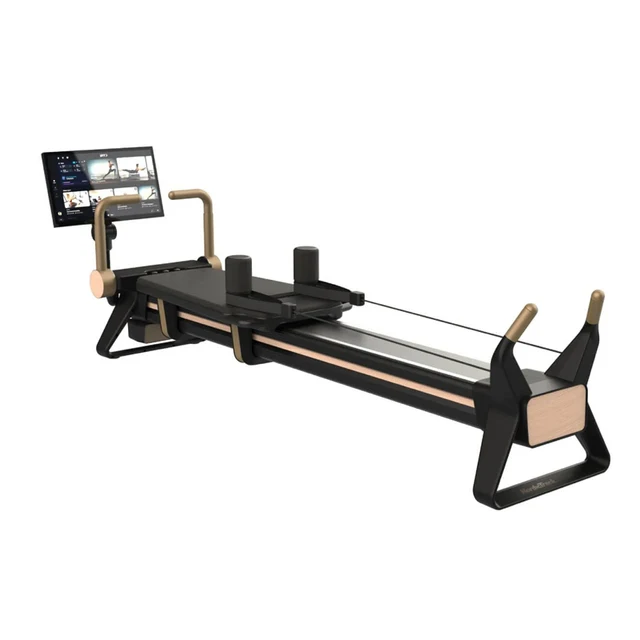 Pilates reformer machine with a padded carriage, foot bars, and a mounted screen for guidance.