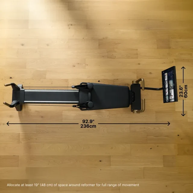 Overhead view of a Pilates reformer on a wooden floor with dimension labels: 236 cm long and about 60 cm wide, plus a space‑around guideline at bottom.