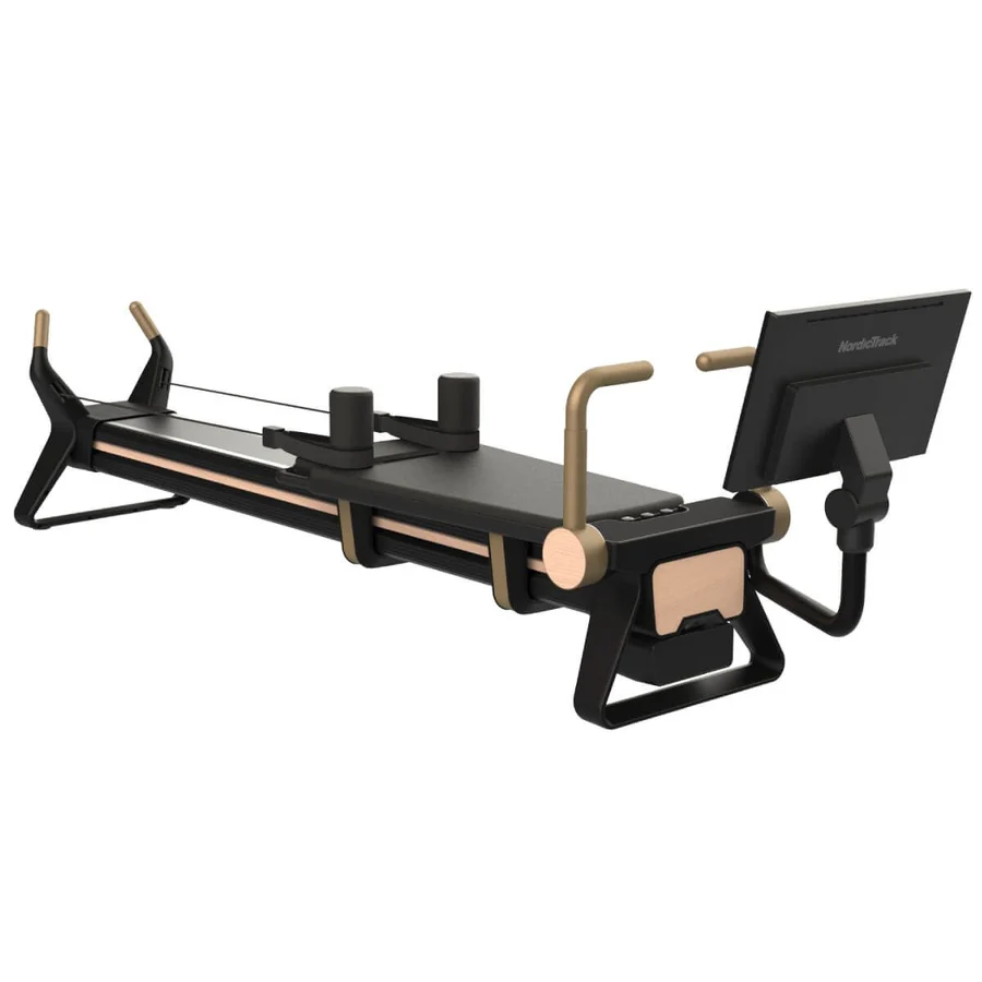 Pilates reformer machine with a sliding carriage, headrest, straps, and a monitor on the side.